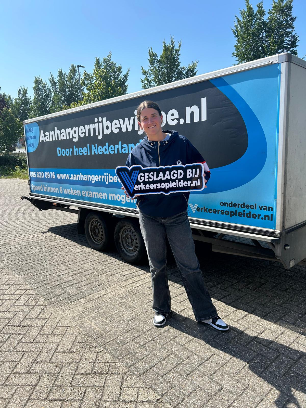 Cursist toont een geslaagd-bord voor de aanhanger na het behalen van het BE-rijbewijs in Rotterdam.