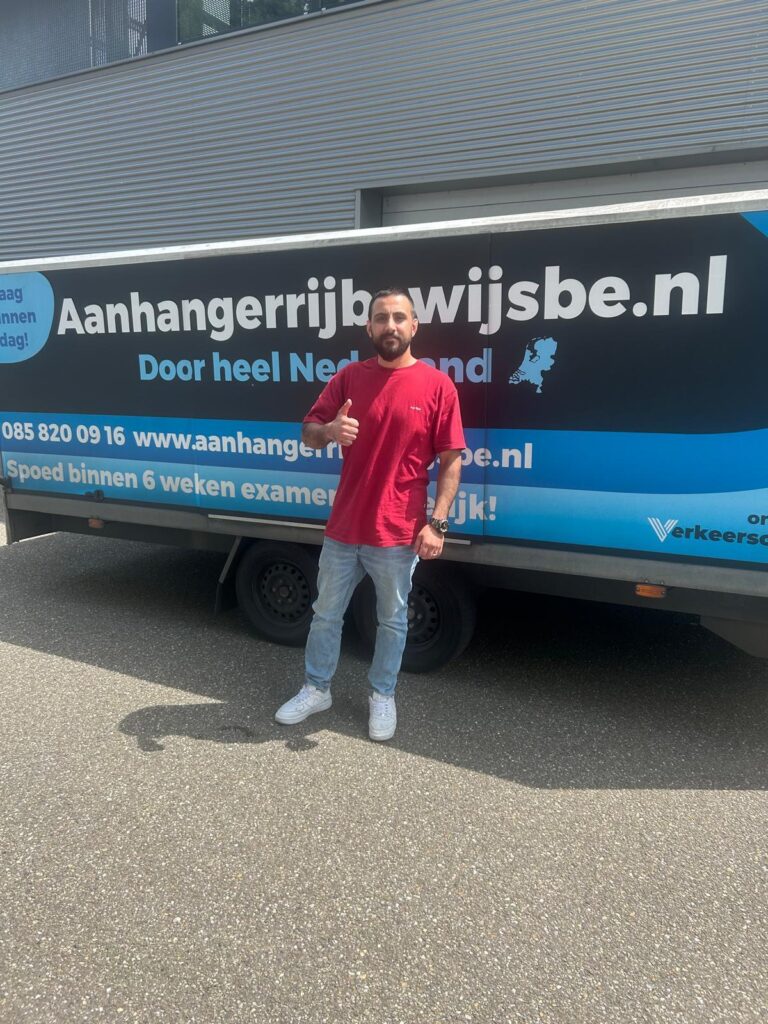 Cursist staat met geslaagd-bord bij de aanhanger na het slagen voor het BE-rijbewijs in Rotterdam.